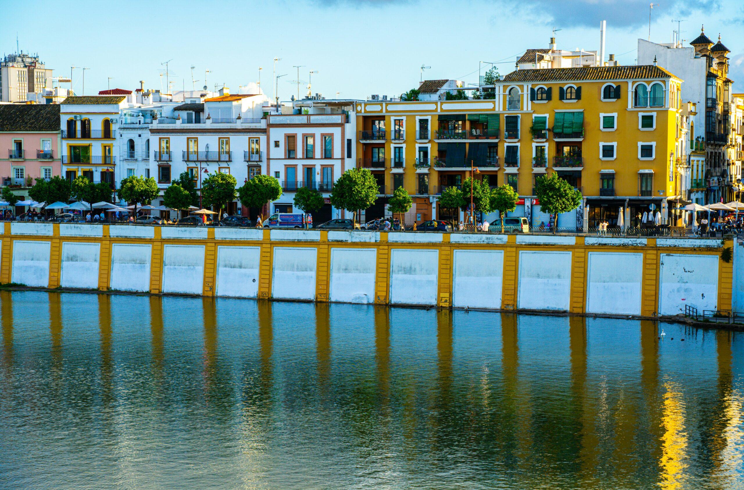 Façades colorées de bâtiments historiques surplombant le fleuve avec des structures portuaires jaunes