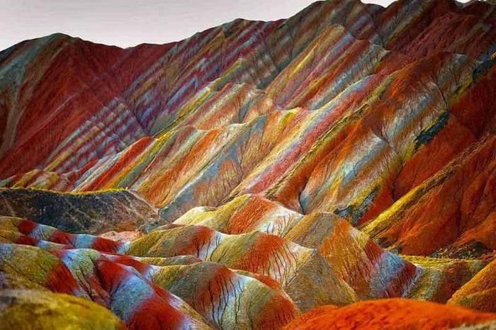 Montagnes aux strates colorées de rouge, orange, jaune et bleu formant des motifs géométriques spectaculaires