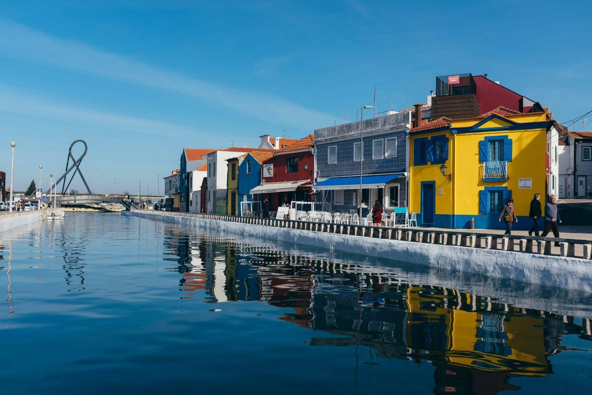 Maisons colorées se reflétant dans un canal calme d’une ville côtière portugaise par beau temps