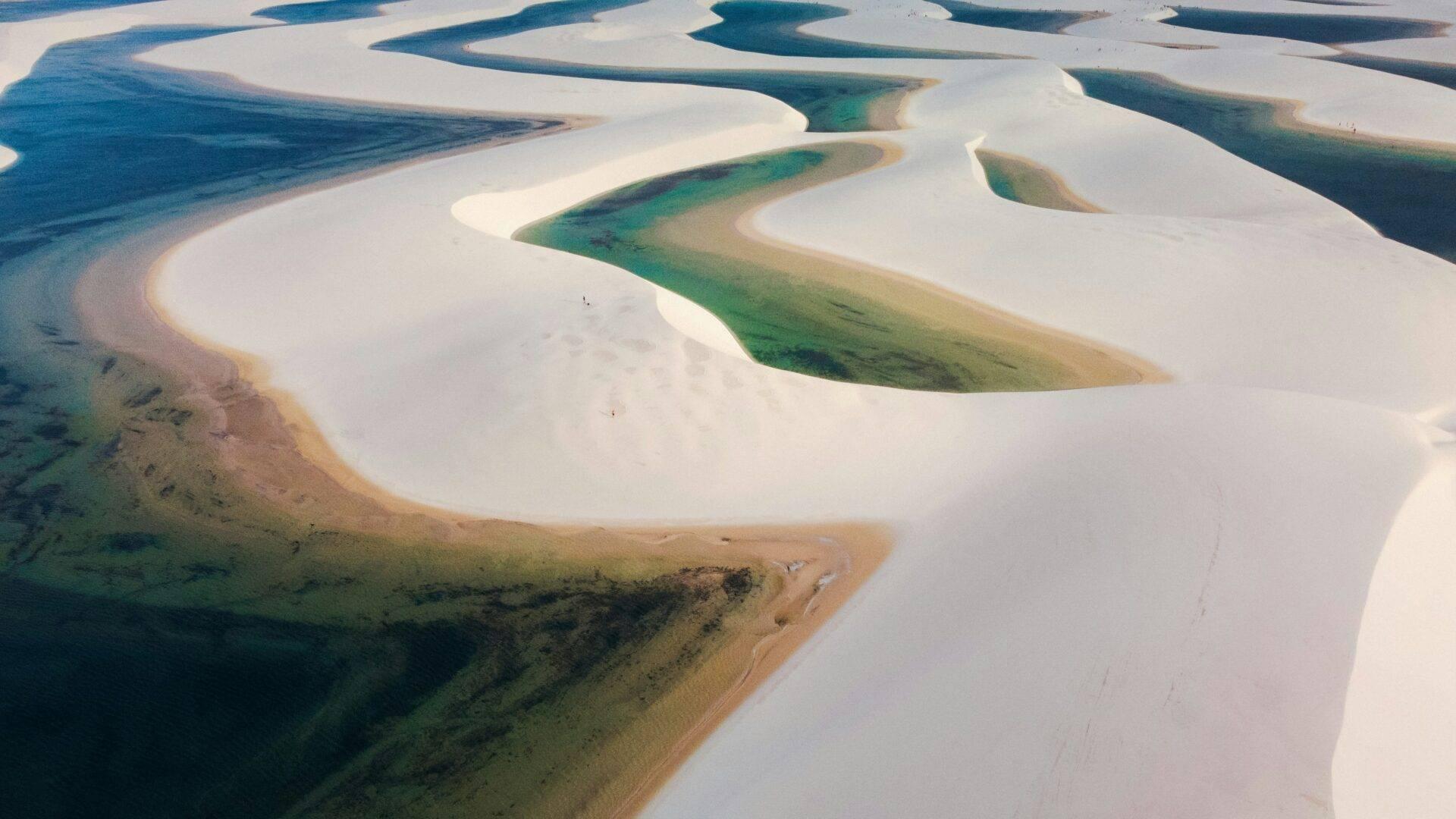 Vue aérienne de lacs d’eau turquoise et de dunes de sable blanc formant un paysage désertique surréaliste