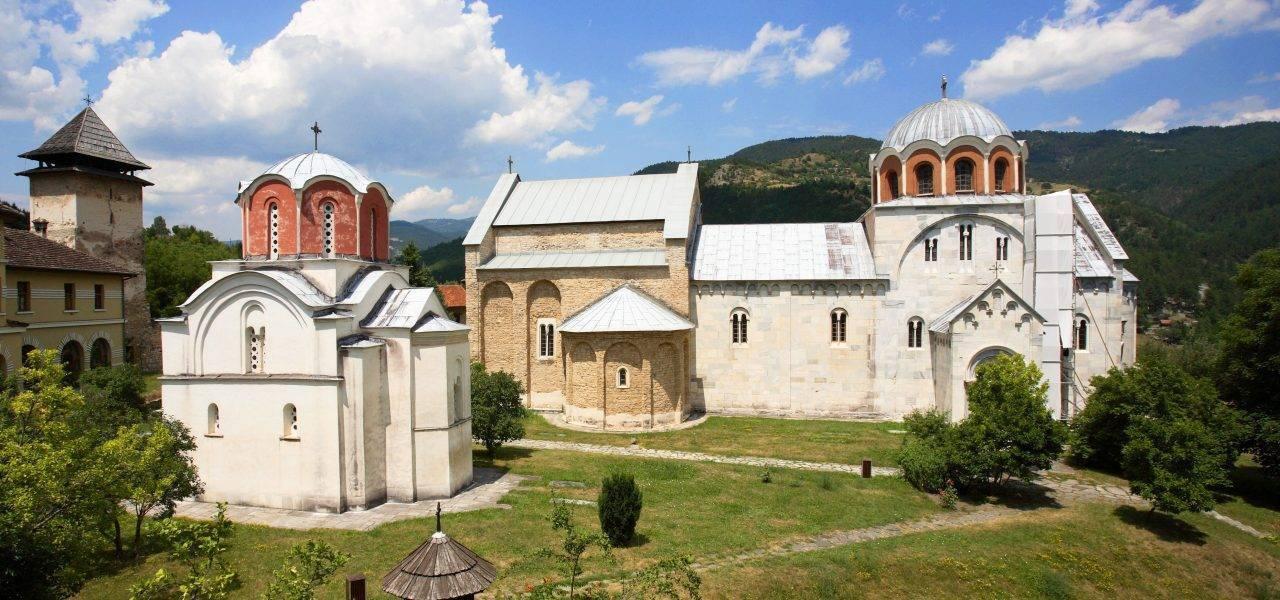Complexe monastique orthodoxe avec églises aux dômes dorés et blancs, entouré de verdure et de montagnes boisées