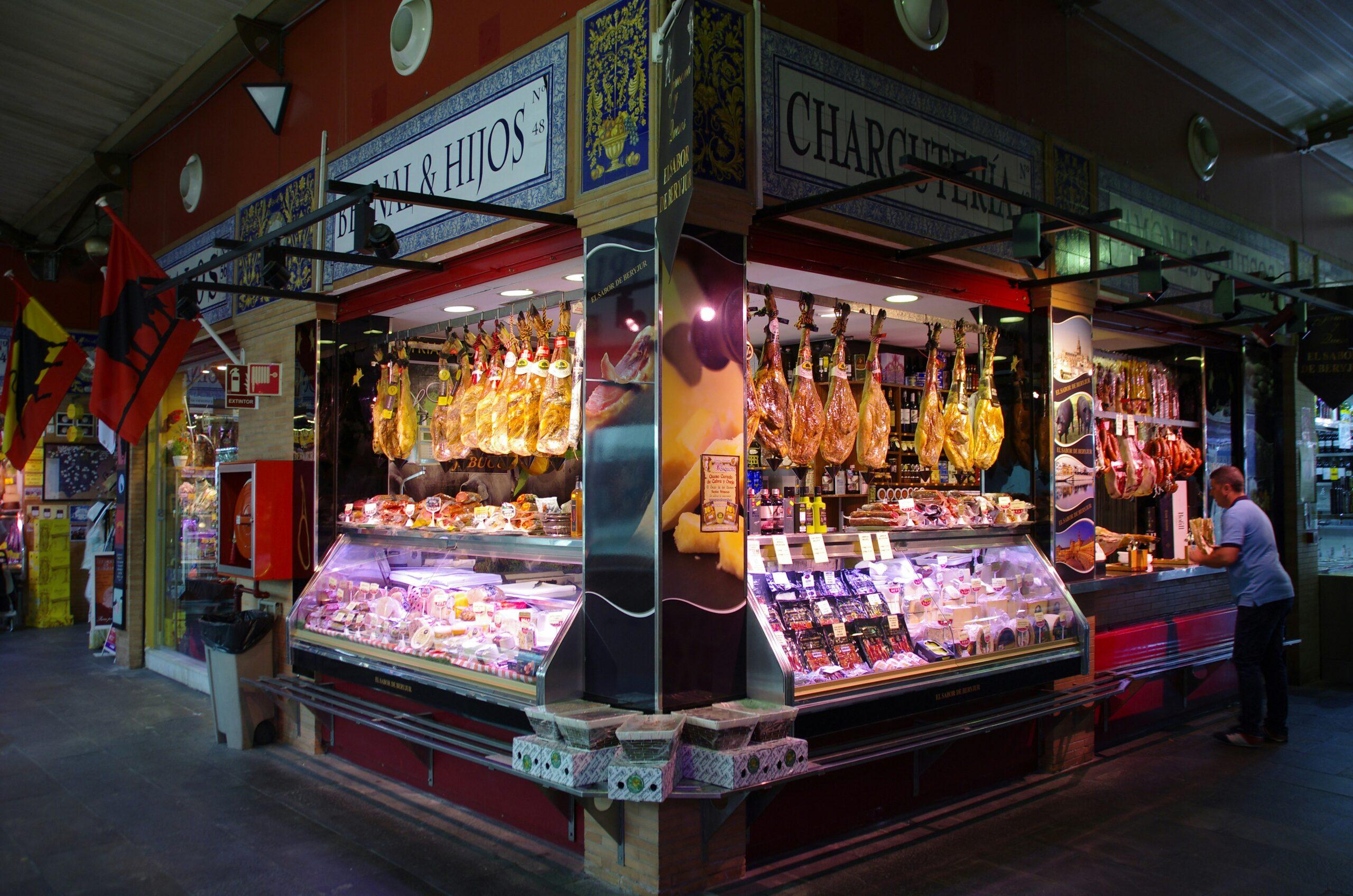 Une charcuterie traditionnelle espagnole avec jambons ibériques suspendus et vitrines réfrigérées de produits de qualité